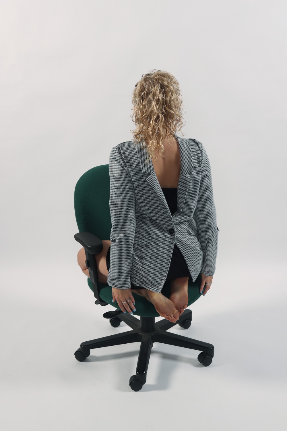 A woman kneeling on a chair backwards wearing her business attire backwards.